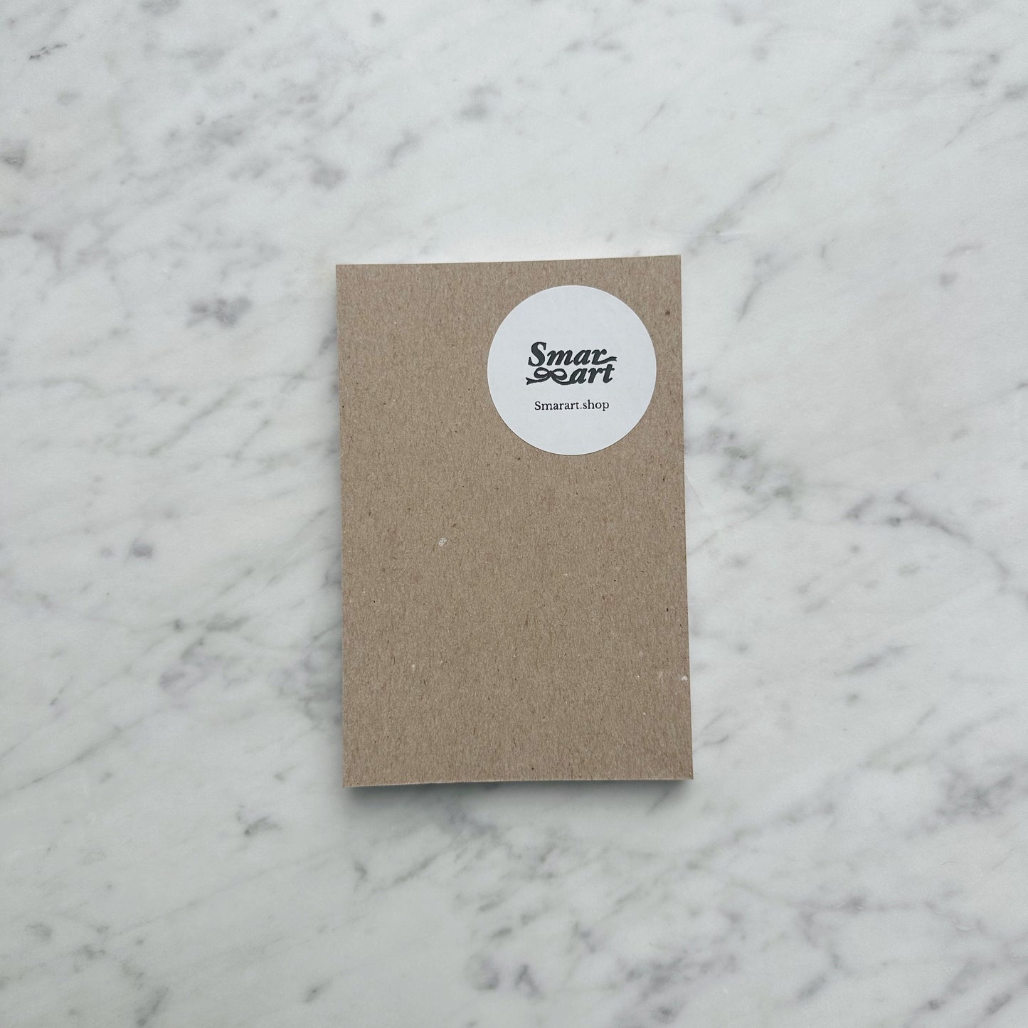 Small brown notebook with a white label on a marble surface
